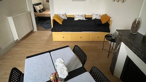 Un salon confortable avec un canapé-lit, une table à manger avec des chaises et un luminaire suspendu.