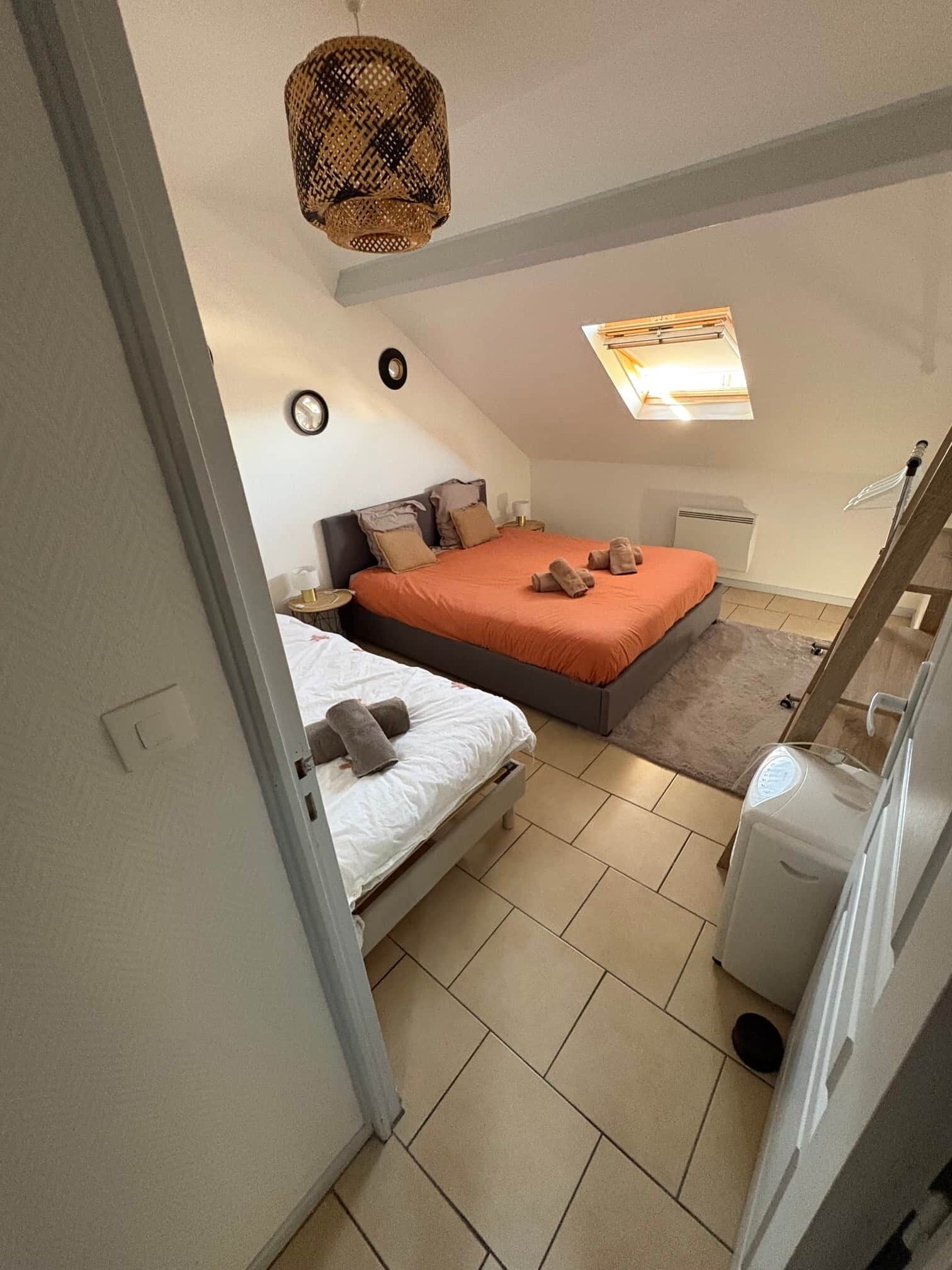A bedroom with two beds, a ceiling fan, a window, and a small heater.