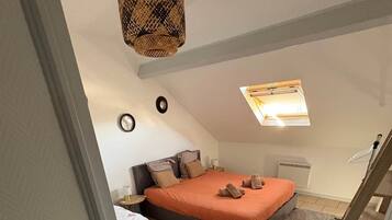 A bedroom with two beds, a ceiling fan, a window, and a small heater.