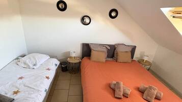 A bedroom with two beds, a hanging light fixture, and a small round table.
