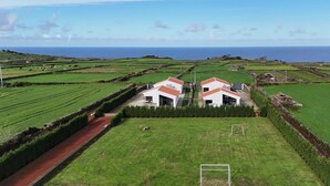 Ein ländliches Anwesen mit zwei weißen Gebäuden, einem grünen Feld und einem Fußballtor.