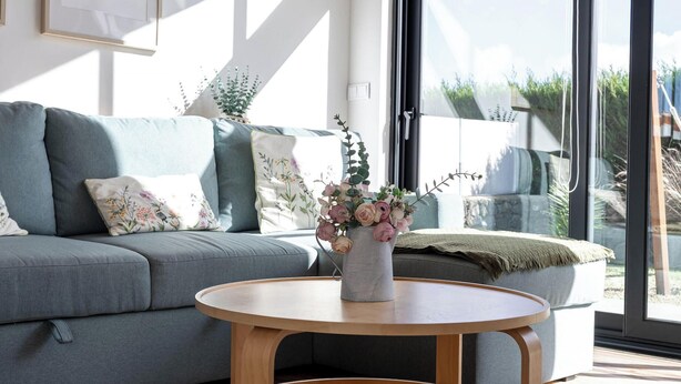 A modern living room with a grey sofa, a wooden coffee table, and a large window with a view of greenery. - Bird House by PontaNegraAzores (Angra do Heroísmo)