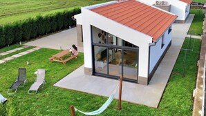 A modern house with a red roof, a glass door entrance, a patio with a table and chairs, and a hammock. - Bird House by PontaNegraAzores (Angra do Heroísmo)