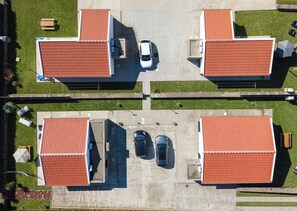Vista aérea de un edificio con dos zonas de estacionamiento, un coche blanco y un coche azul estacionados.