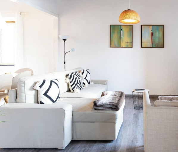 A modern living room with a sectional sofa, a small round table, and two abstract paintings on the wall.