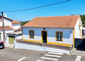 A small, single-story building with a tiled roof, a front door, and two windows.