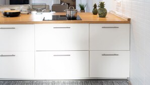 A modern kitchen with white cabinetry, a wooden countertop, a built-in stove, and pendant lighting. - Casa da Gente T2 by PontaNegraAzores (Praia da Vitória)