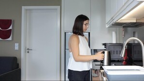 Una cocina moderna con un refrigerador, una cafetera y un lavamanos.