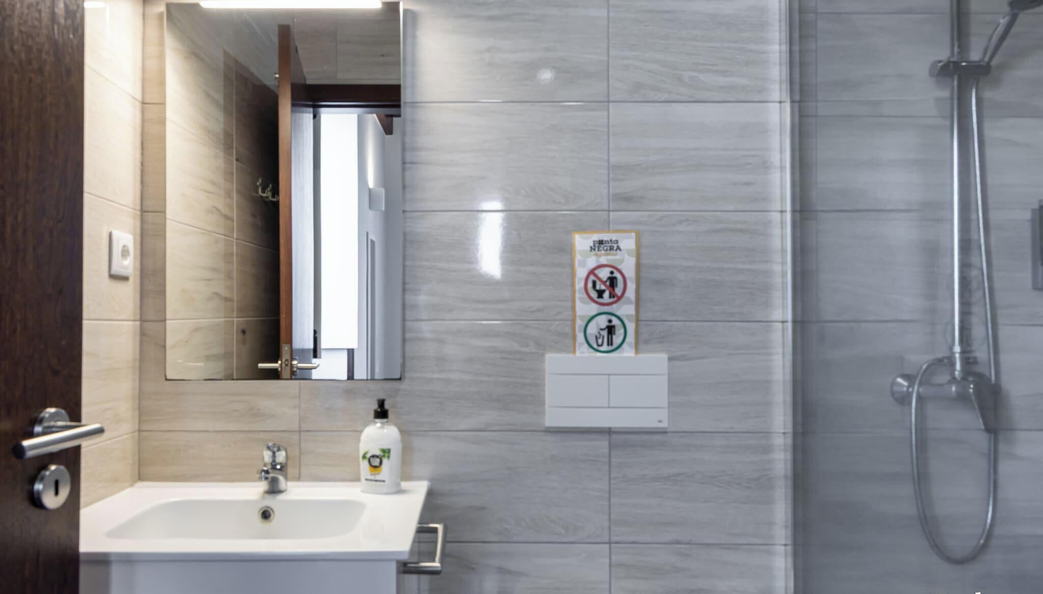 A bathroom with a sink, mirror, and shower.