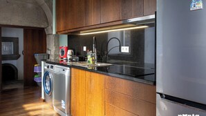 Eine Küche mit Holzausstattung, einem Edelstahl-Kühlschrank, einer Waschmaschine und einem Spülbecken.