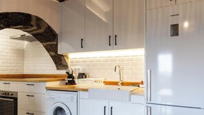A modern kitchen with white cabinets, a built-in washing machine, and a stainless steel refrigerator. - Charming Country House by PontaNegraAzores (Angra do Heroísmo)