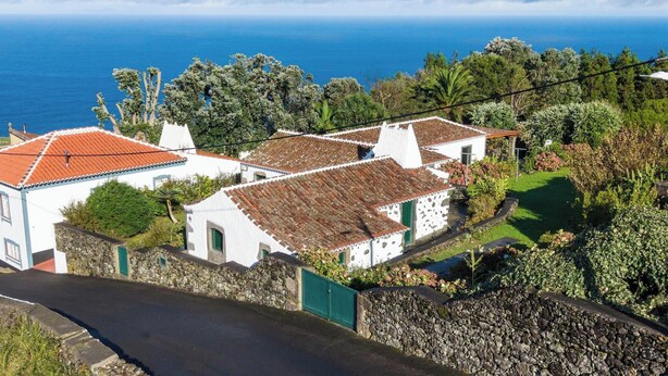 Un pueblo costero con edificios blancos tradicionales, un muro de piedra y vistas al mar.