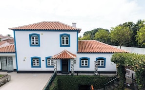 Um edifício de dois andares com telhado de telhas, várias janelas e uma pequena entrada.