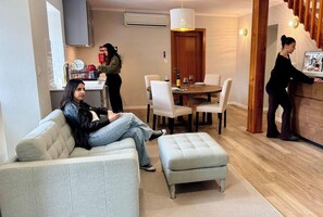 Una sala de estar con sofá, reposapiés y una zona de comedor con sillas y mesa.