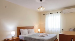 Een hotelkamer met een bed, nachtlampjes, een bureau en een airconditioningsysteem.