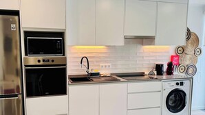 Una cucina moderna con elettrodomestici in acciaio inossidabile, forno a incasso, microonde, lavello e lavatrice.