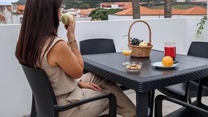 Eine Person sitzt an einem Tisch mit einem Korb, einem Glas Orangensaft, einem Glas rotem Saft und einer Schüssel Frühstücksflocken.