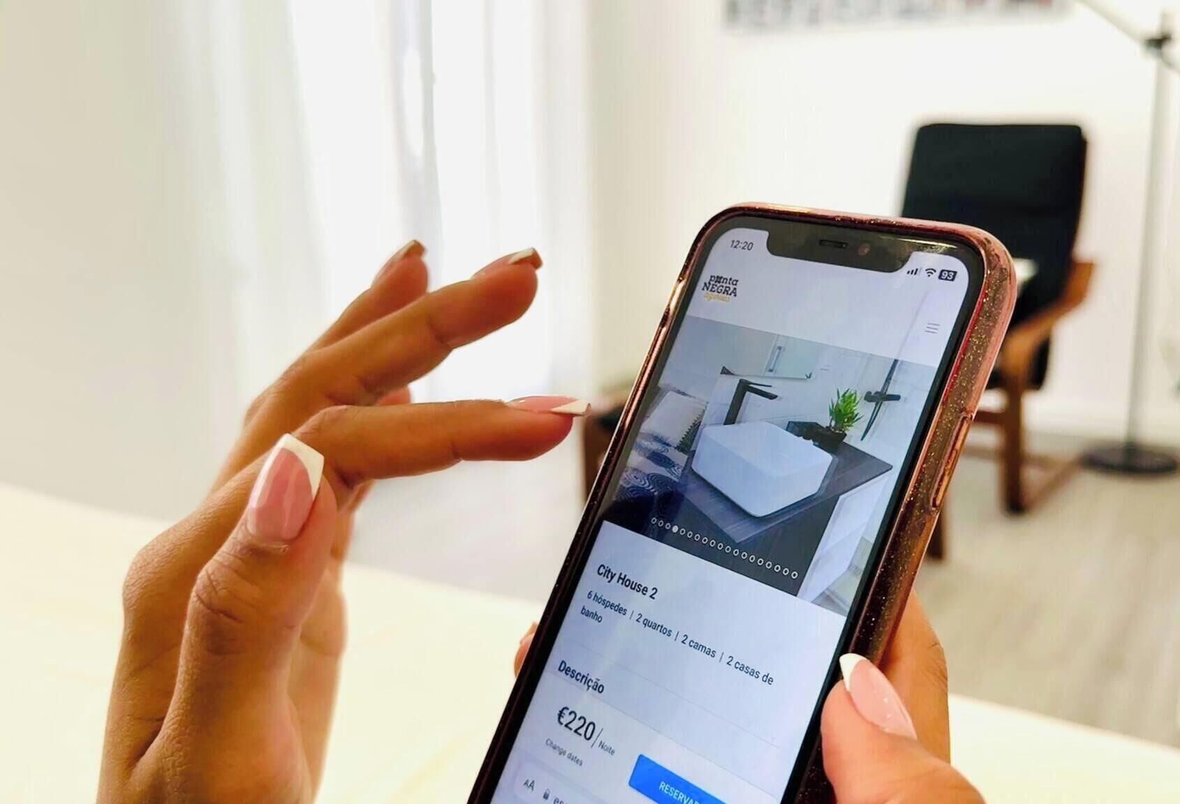 A smartphone displaying a hotel listing with a modern interior, a bed, and a bathroom.