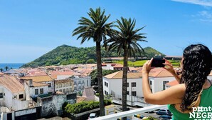 Eine Person fotografiert eine Küstenstadt mit Gebäuden und Palmen.