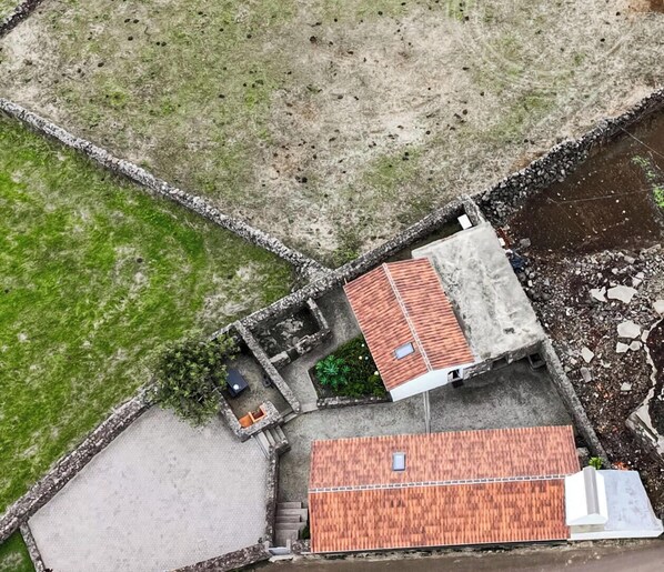 A building with a red-tiled roof, a small garden area, and a paved courtyard.