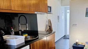 Eine moderne Küche mit schwarzer Arbeitsplatte, Spüle aus Edelstahl und Holzschränken.