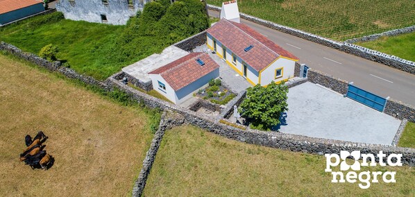 Une maison à deux étages, avec un toit recouvert de tuiles rouges, un mur en pierre et une allée pavée.