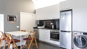 Een moderne keuken met witte kastjes, een ingebouwde magnetron, een roestvrijstalen koelkast, een vaatwasser en een wasmachine.
