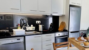 Een moderne keuken met een vaatwasser, fornuis, koffiezetapparaat en een koelkast.