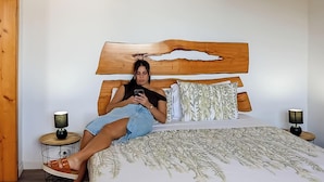 Ein Bett mit Holz Kopfteil, einer gemusterten Bettdecke und zwei Nachttischlampen.