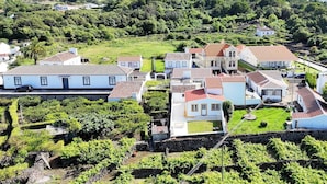 Área residencial com casas, algumas com telhados de telha vermelha, cercada por vegetação e colinas.