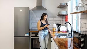 A modern kitchen with a stainless steel refrigerator, oven, and dishwasher, wooden countertops, and a window providing natural light. - The Biscuit House T2 by PontaNegraAzores (Praia da Vitória)