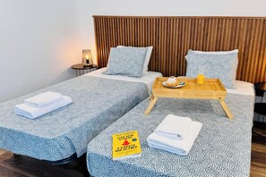 A double bed with patterned bedding, a bedside table with a tray, and a small lamp.