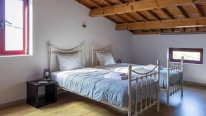 Ein Schlafzimmer mit zwei Betten, Holzboden, einem Fenster und einem Nachttisch.
