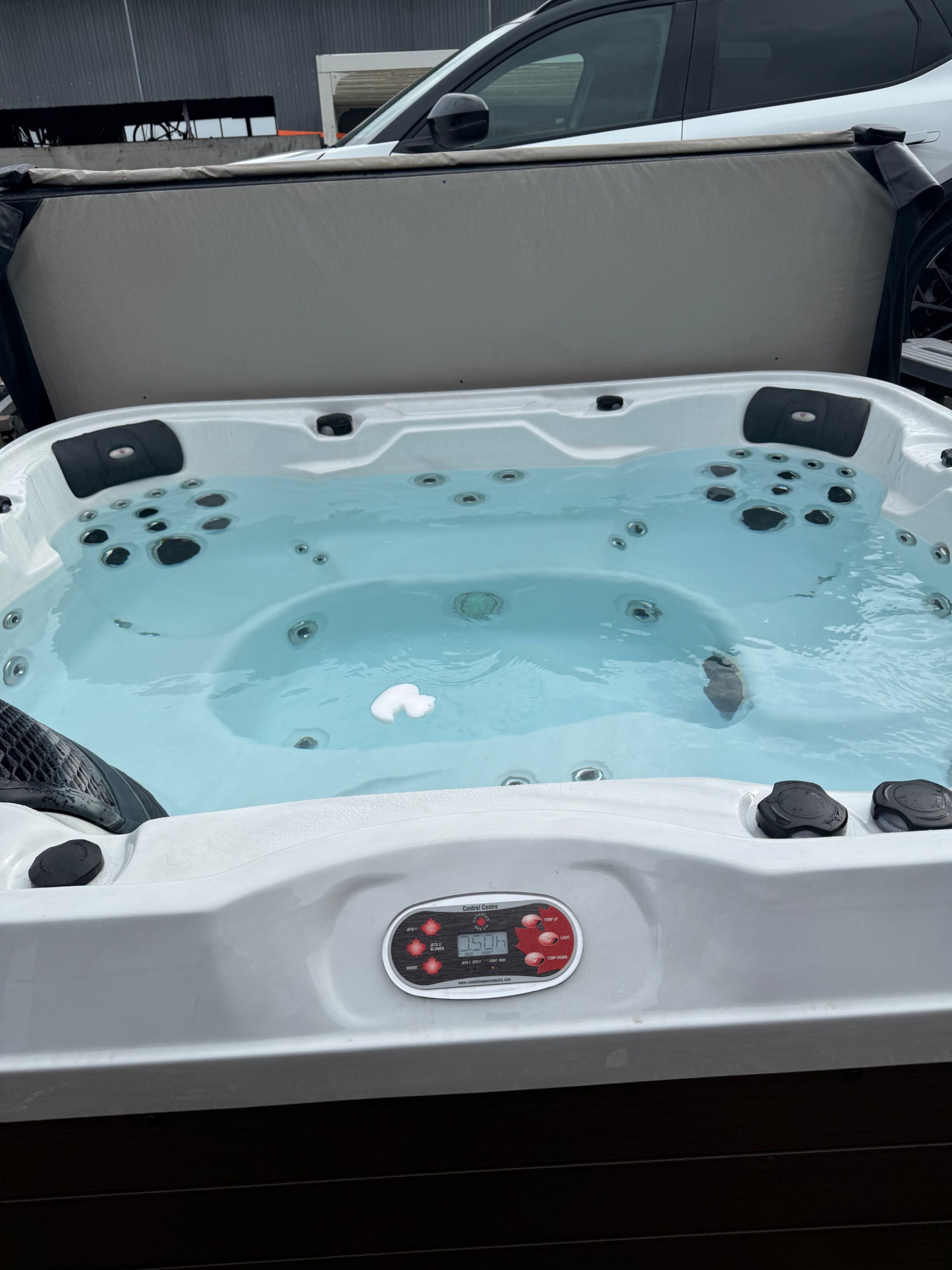 Uma banheira de hidromassagem com painel de controle, vários jatos e superfície aquática transparente.