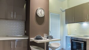 A modern kitchen with a built-in oven, a wall clock, and a window with blinds. - Speranza by halu! (Thessaloniki)