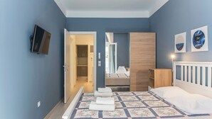 A bedroom with a bed, a TV, and a door leading to a bathroom. - Speranza by halu! (Thessaloniki)