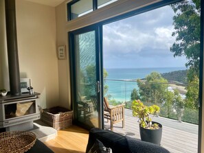 A modern living room with a large sliding glass door leading to a balcony with a view of the ocean. - Wye Wander (Wye River)