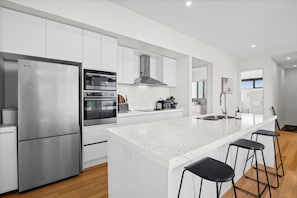 Une cuisine moderne dotée d’un grand îlot central, d’appareils électroménagers en acier inoxydable et d’un design minimaliste.