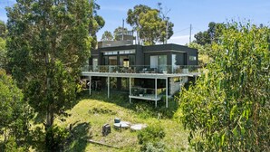A modern two-story house with a balcony and a garden.