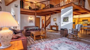 Un espacio habitable amplio con una escalera de madera, un tapete grande y una acogedora disposición de asientos.