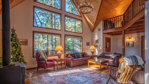 Amplia sala de estar con ventanas grandes, chimenea y un rincón de descanso acogedor.