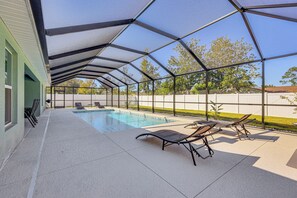 A covered outdoor swimming pool area with lounge chairs and a clear view of the surrounding landscape. - 8 Mi to Flagler Beach: Home w/ Outdoor Dining! (Palm Coast)