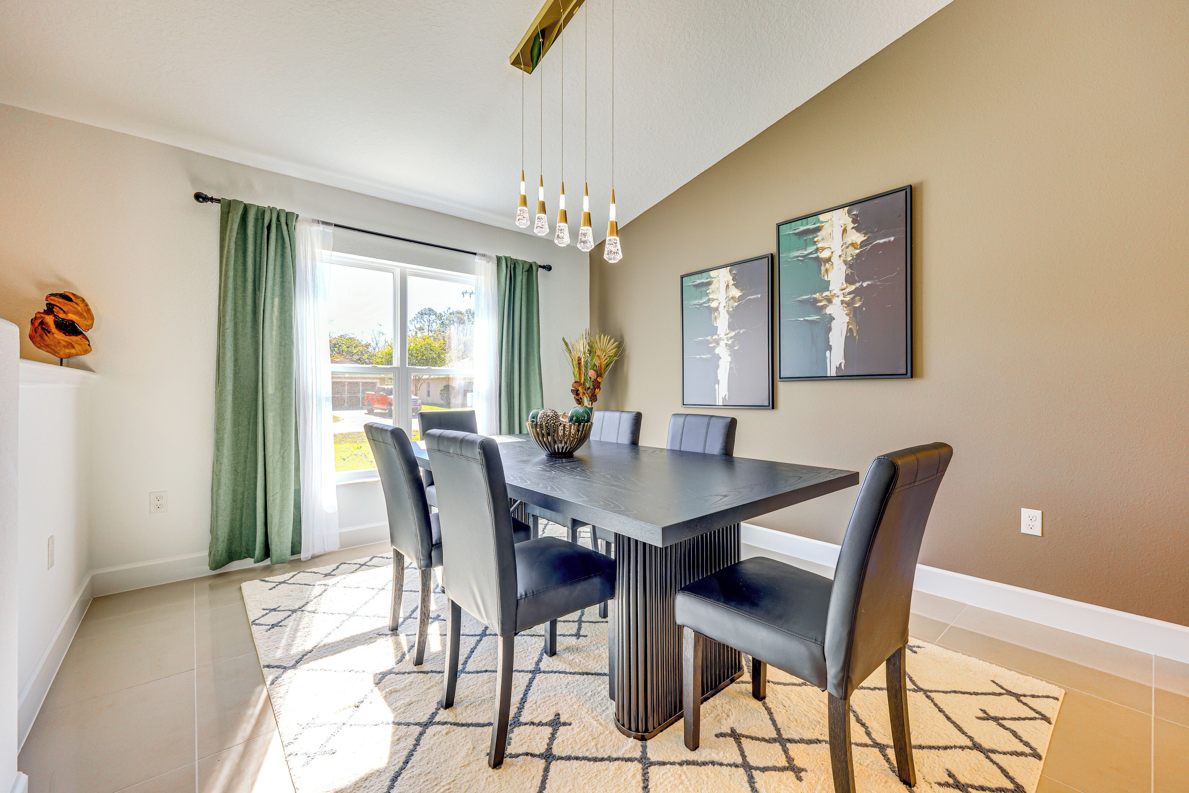 Ein Essbereich mit einem rechteckigen Tisch, sechs Stühlen, einer Vase mit Blumen und zwei gerahmten Kunstwerken an der Wand.