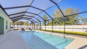A covered swimming pool with a clear blue water, surrounded by a white fence and trees. - 8 Mi to Flagler Beach: Home w/ Outdoor Dining! (Palm Coast)