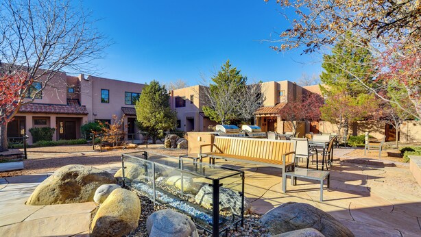 Un espace extérieur aménagé en patio, avec des sièges, un élément décoratif aquatique et de gros rochers.