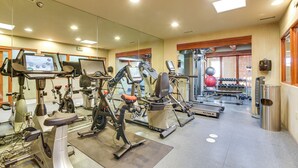 Une salle de sport équipée de divers appareils d’exercice, notamment des tapis de course, des vélos d’appartement et des appareils de musculation.