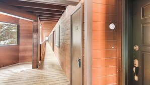 Un couloir aux murs et aux portes en bois, qui mène à une porte verte dotée d’une sonnette et d’un trou de serrure.