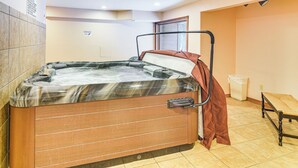 Un bain à remous dans une pièce dont le sol est carrelé, qui possède une fenêtre et une poubelle.
