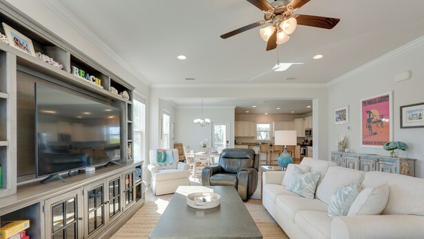 A spacious living room with a flat-screen TV, a ceiling fan, and a dining area with a table and chairs. - Endless Summer: Windmark Beach Home Steps to Shore (Port St. Joe)