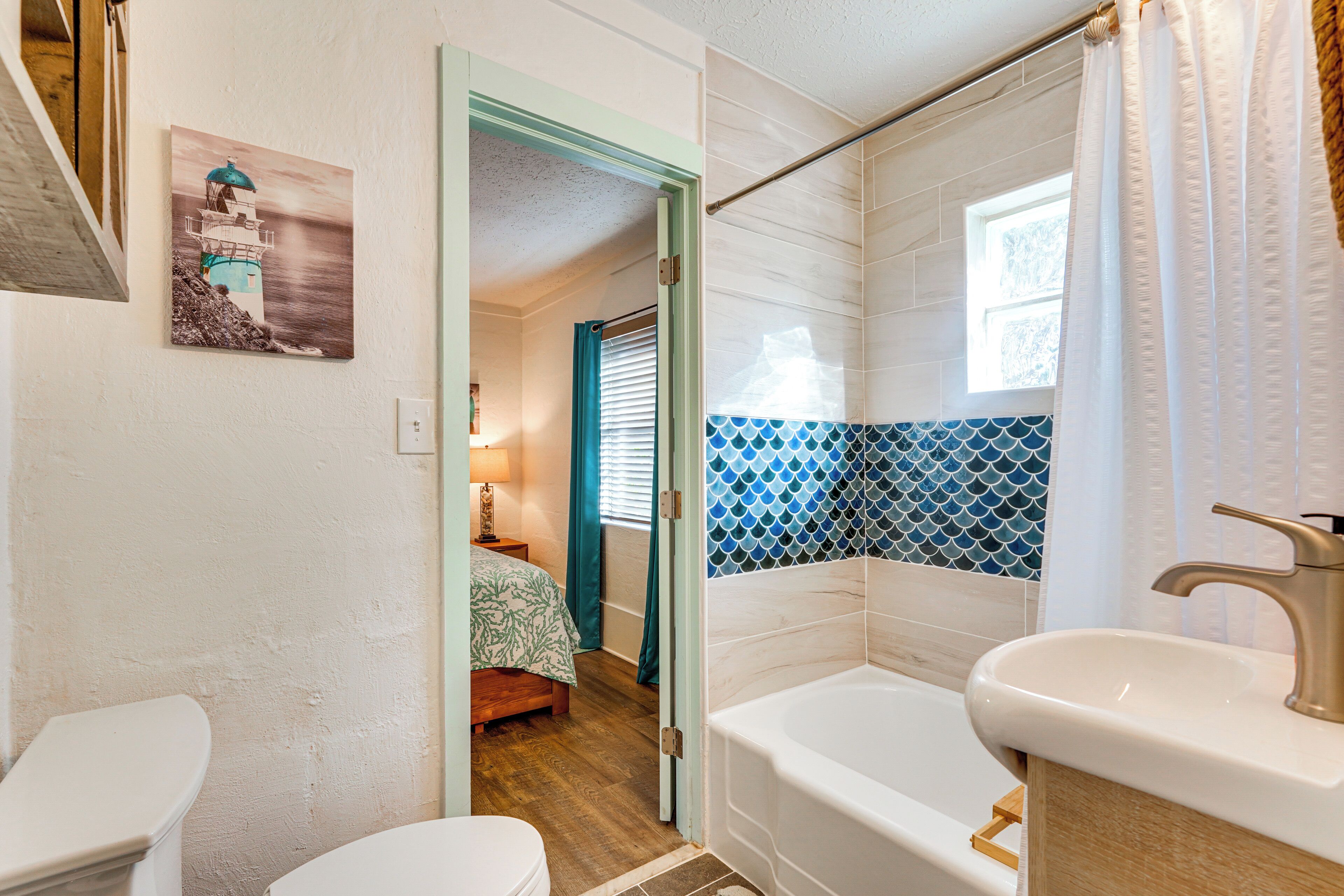 A bathroom with a bathtub, two sinks, and a door leading to a bedroom.